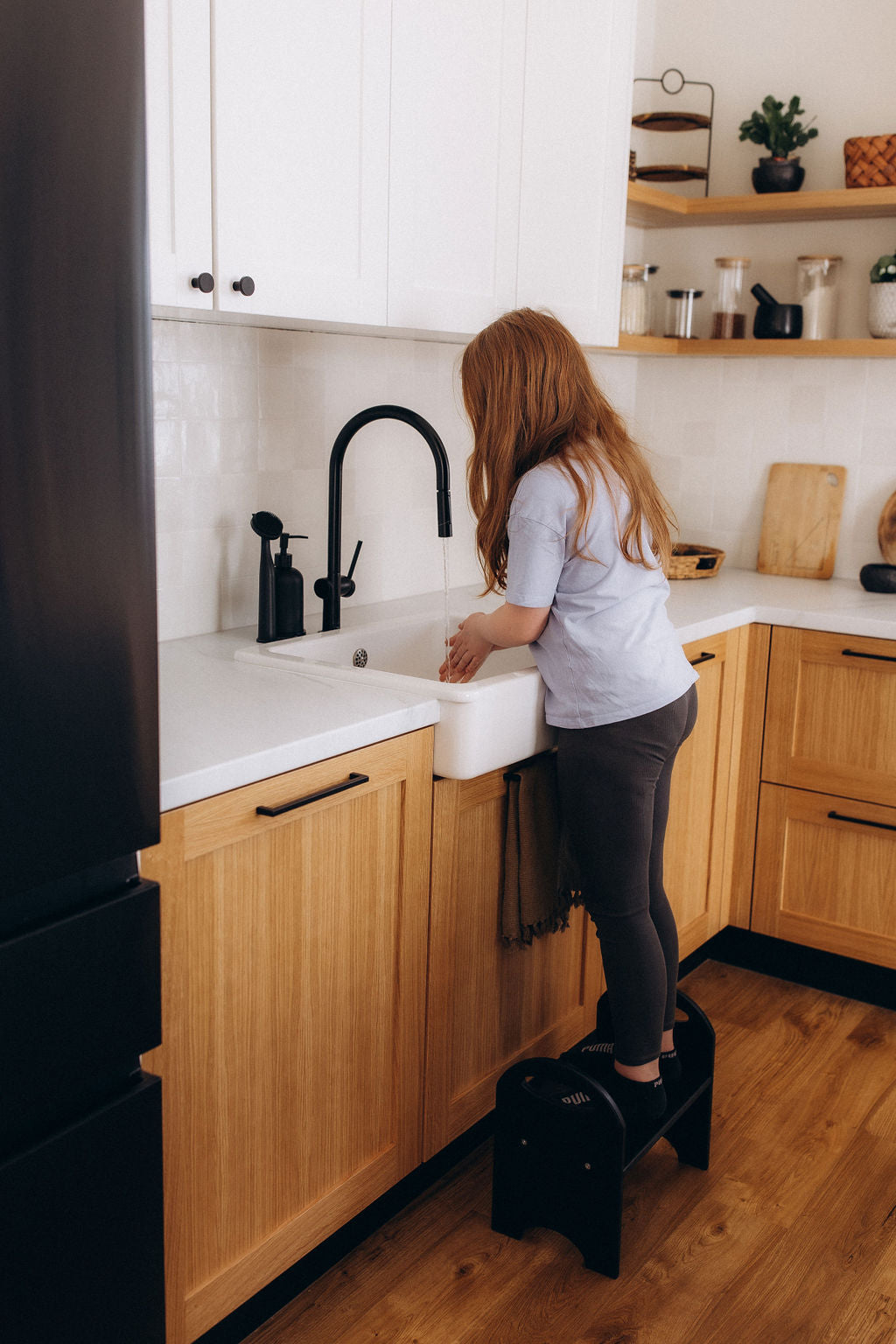 Child using wooden step stool in kitchen