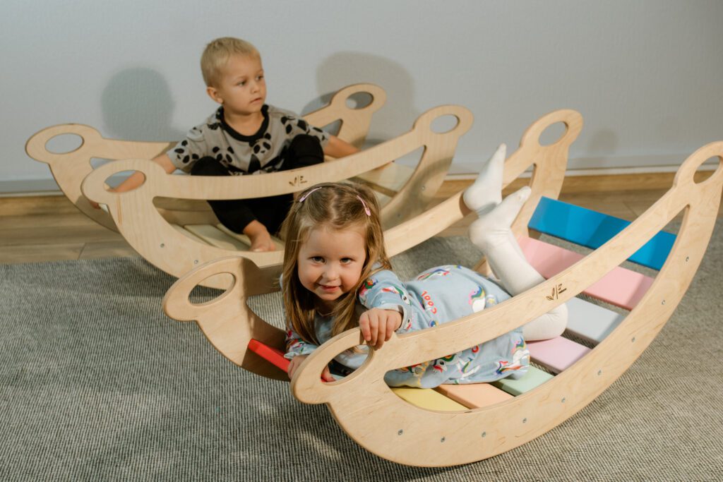 Koka šūpoļu arkā spēlējas divi bērni.